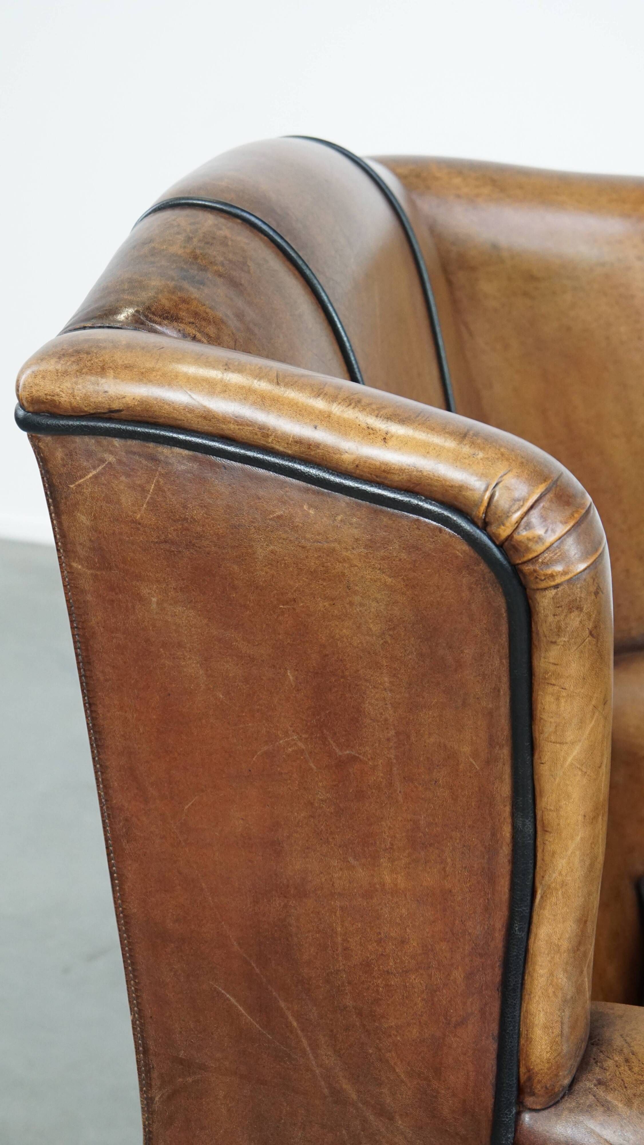 Cognac-colored sheep leather wingback chair finished with black piping