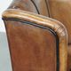 Cognac-colored sheep leather wingback chair finished with black piping