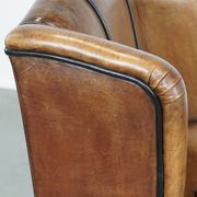 Cognac-colored sheep leather wingback chair finished with black piping
