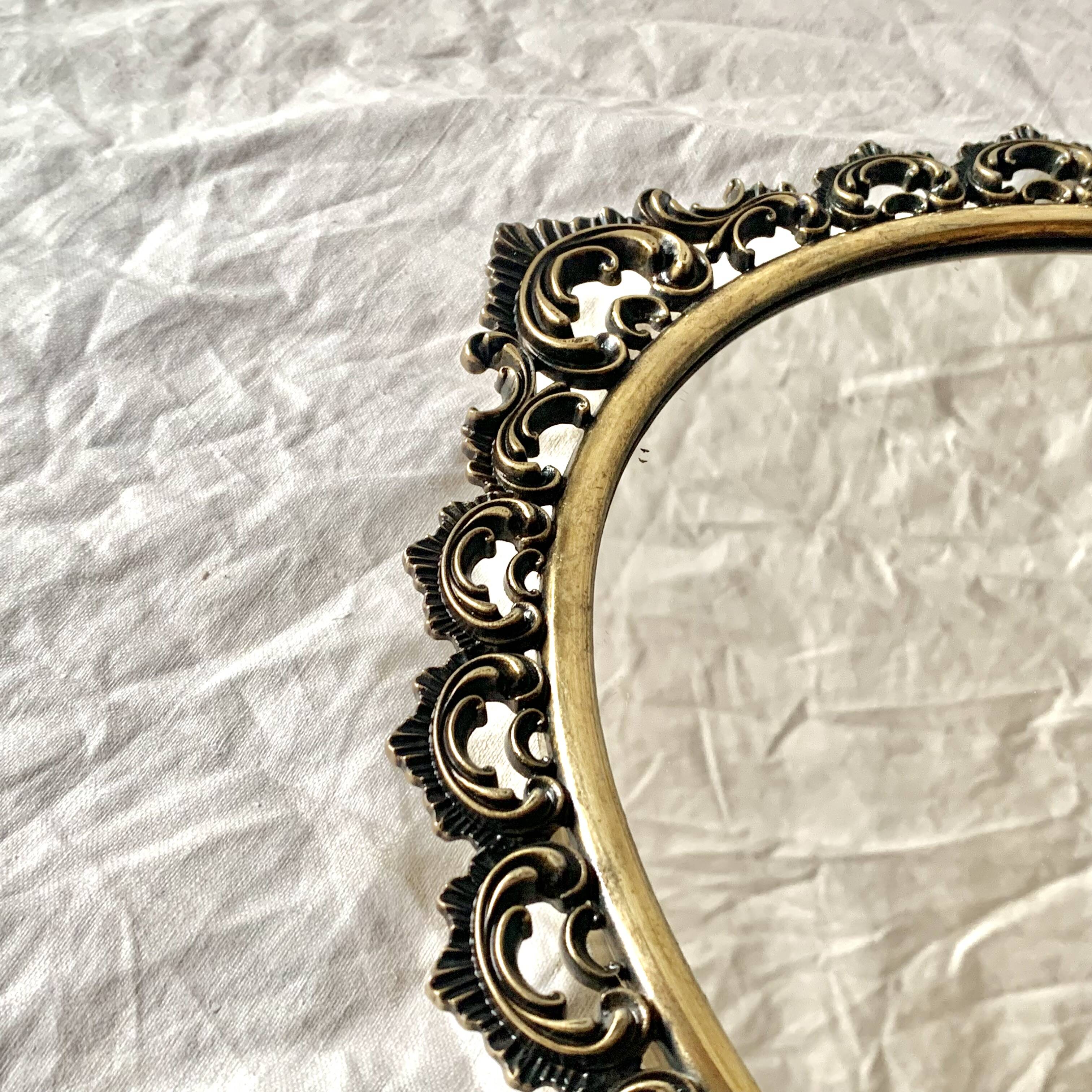 Old oval wall mirror in gilded brass