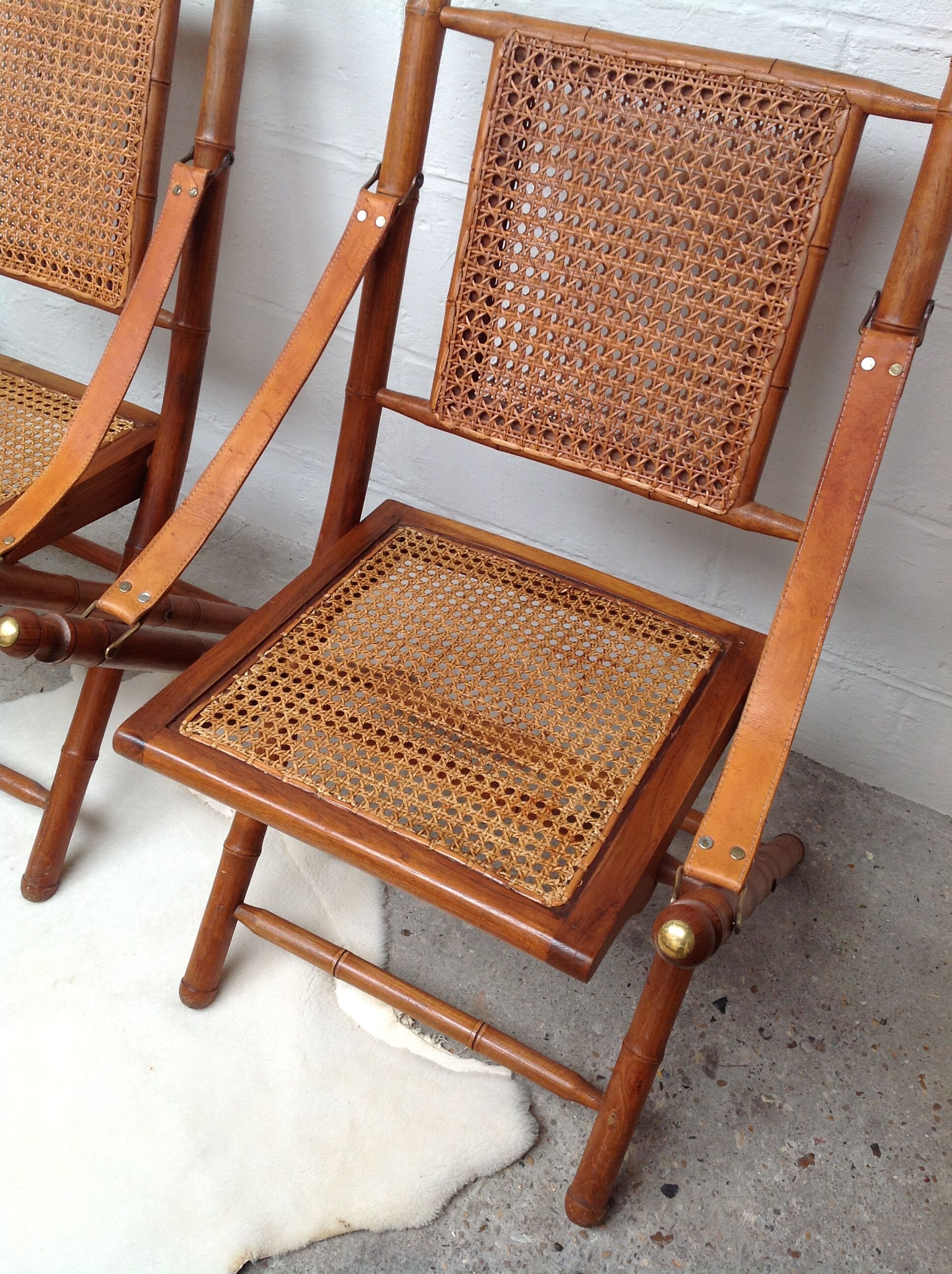 Pair of folding chairs in bamboo and caning, leather and brass