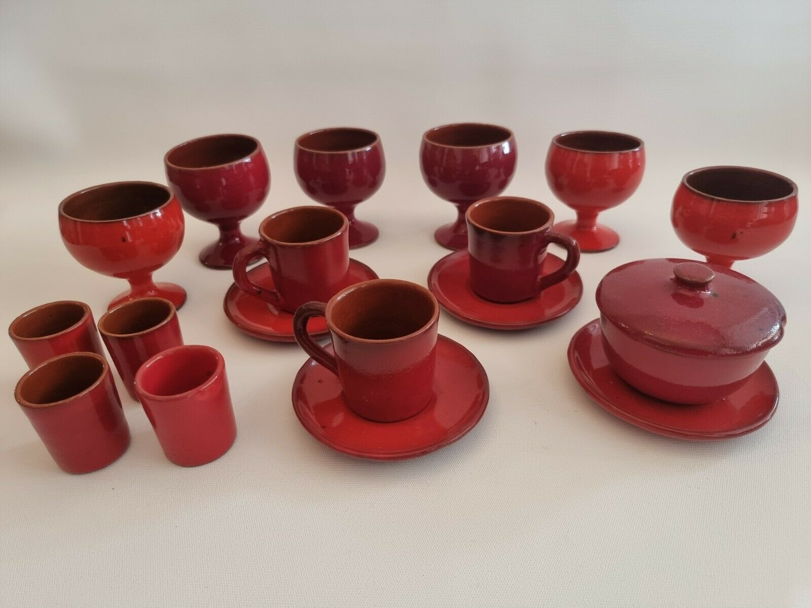 Red enamelled terracotta: cups, saucers, glasses