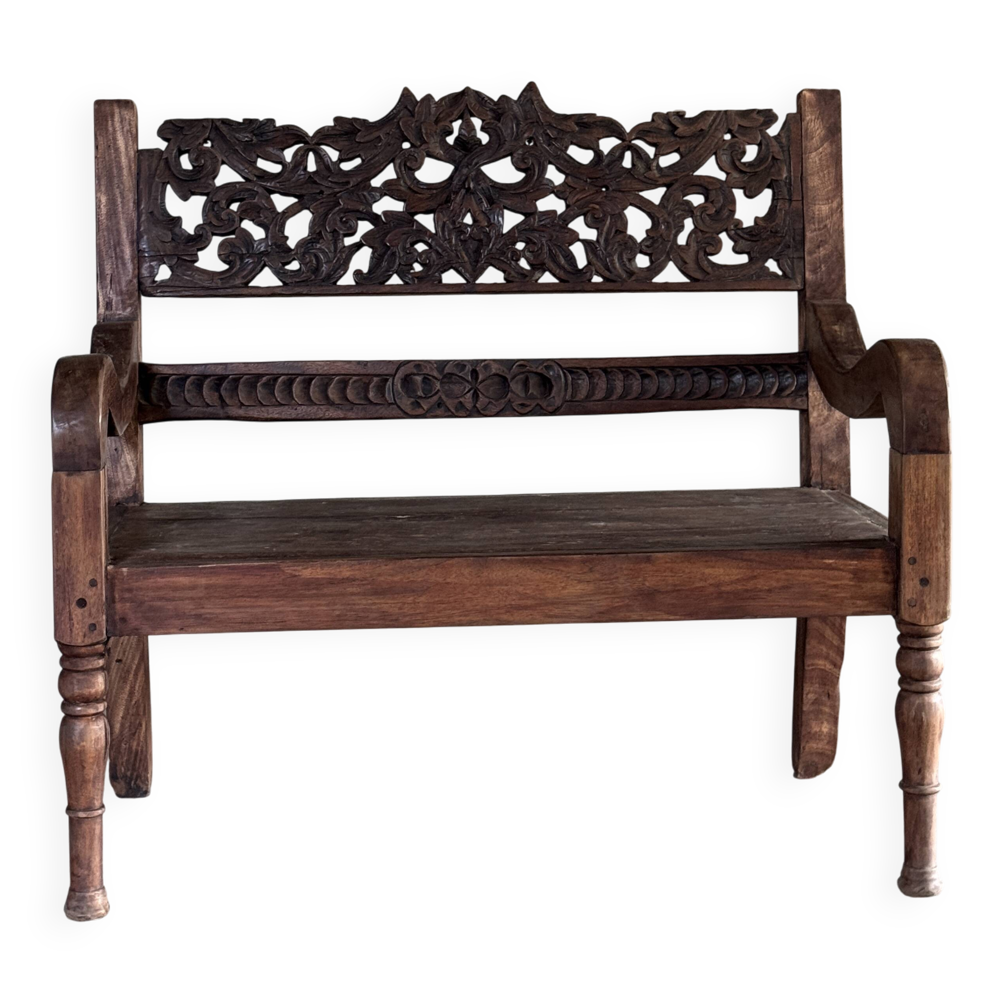 Small antique Indonesian bench in carved teak with plant and floral motifs.