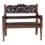 Small antique Indonesian bench in carved teak with plant and floral motifs.