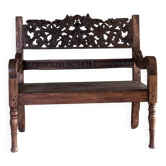 Small antique Indonesian bench in carved teak with plant and floral motifs.