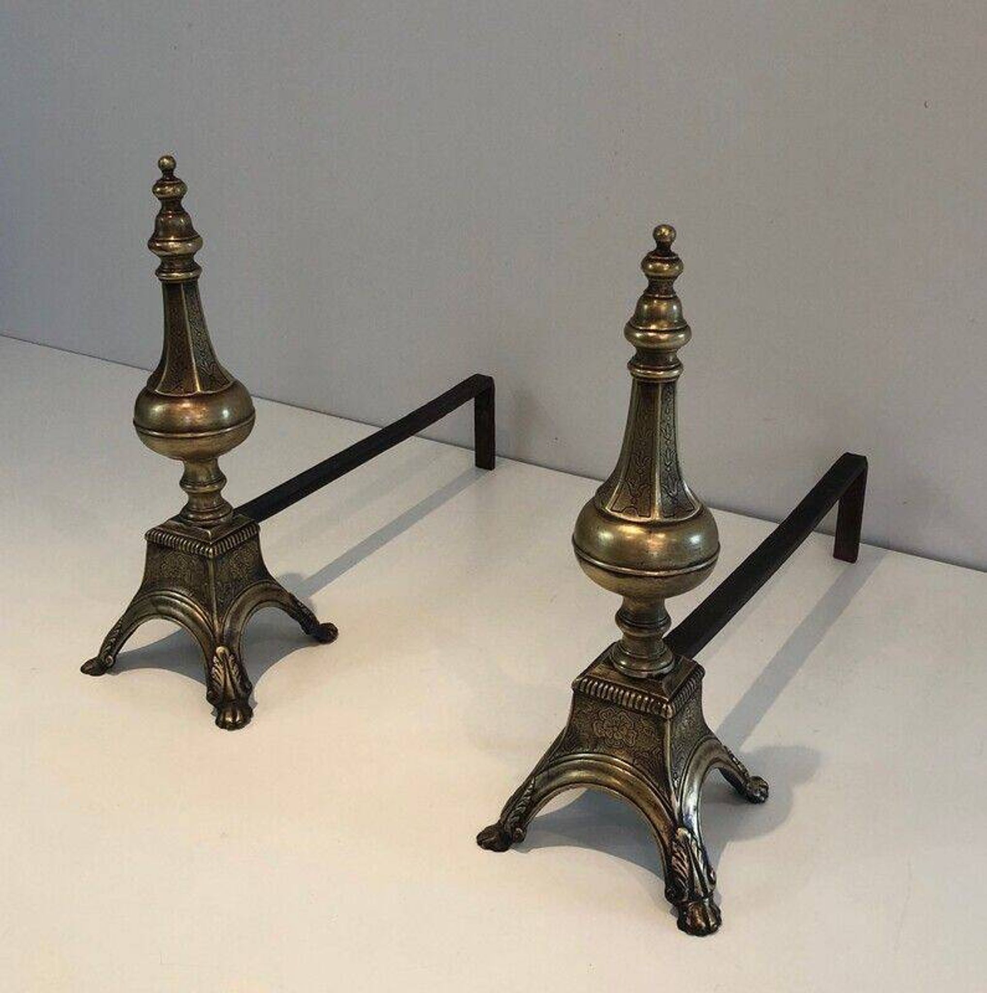 Pair of chiselled bronze and wrought iron fire dogs in the Louis XVI style.