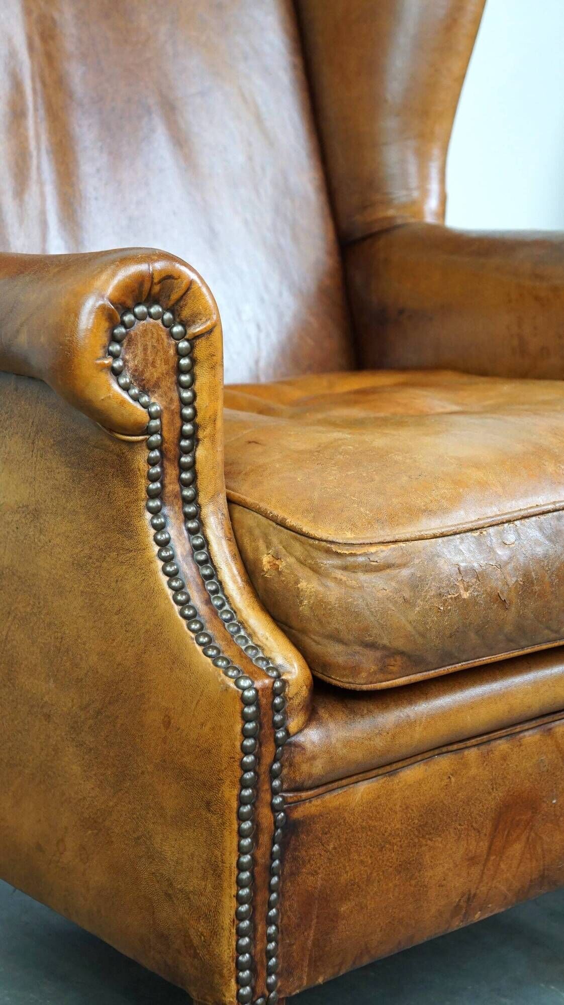 Positively lived-in sheepskin leather wing chair with pleasant seating comfort