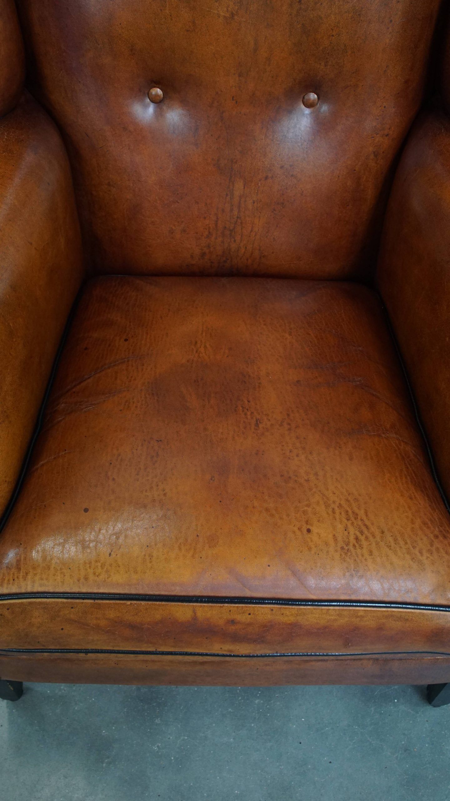 Sheepskin wingback armchair with stitching and black piping
