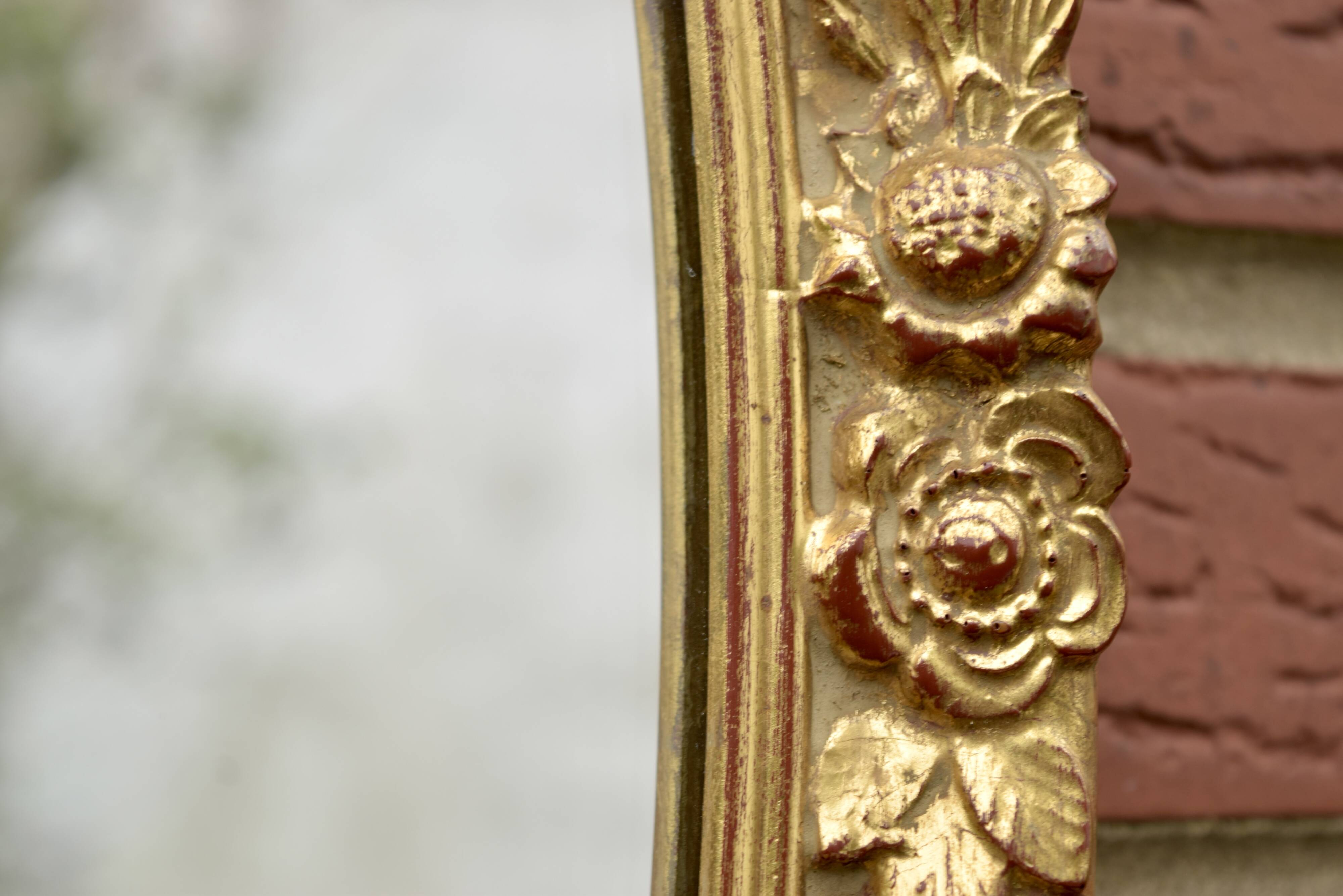 Old large oval wall mirror in golden resin