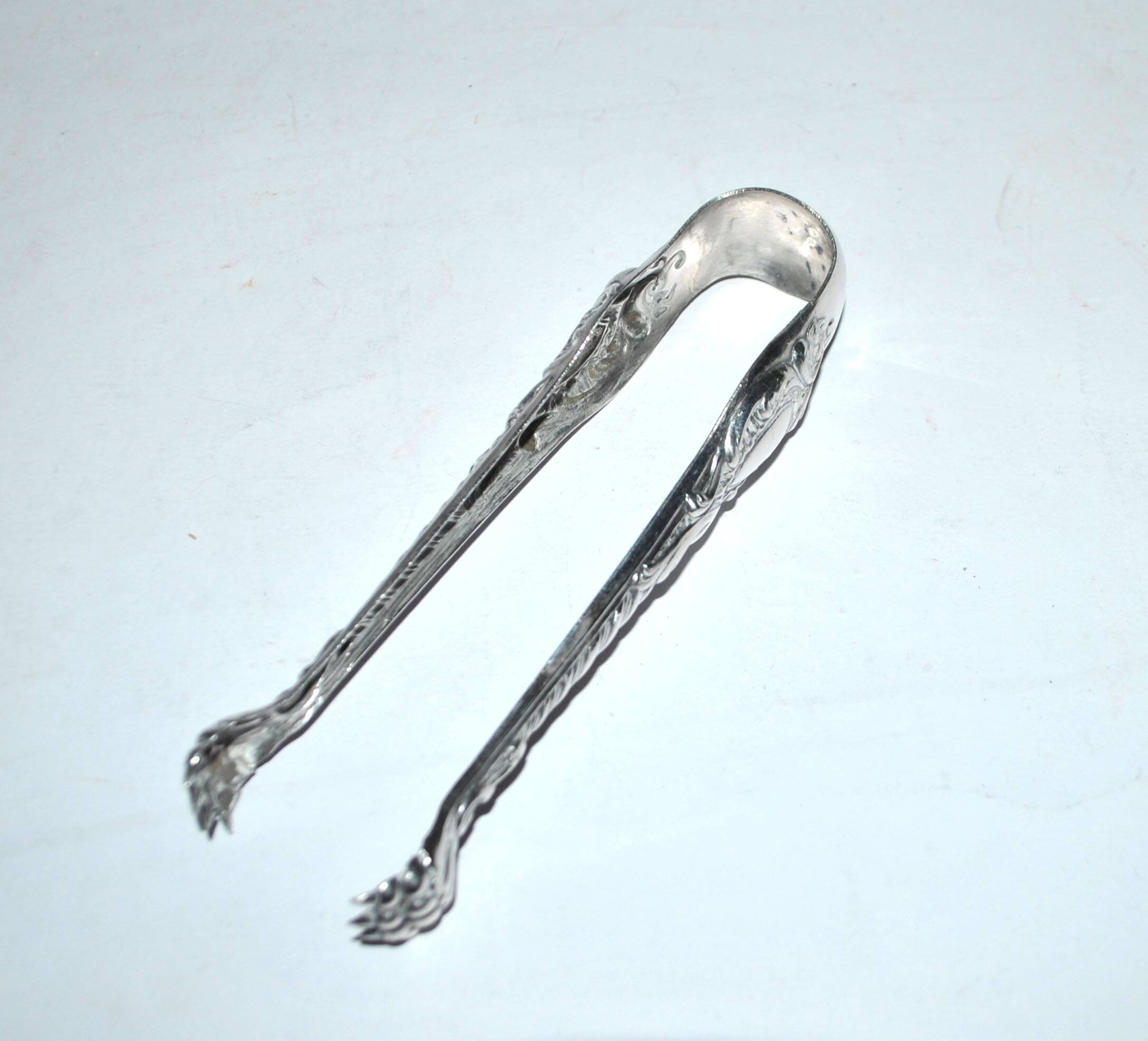 Rocaille sugar tongs in silver metal with lion claw medallion