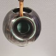 A ceramic jug with a metallic glaze and a handle made of woven raffia.