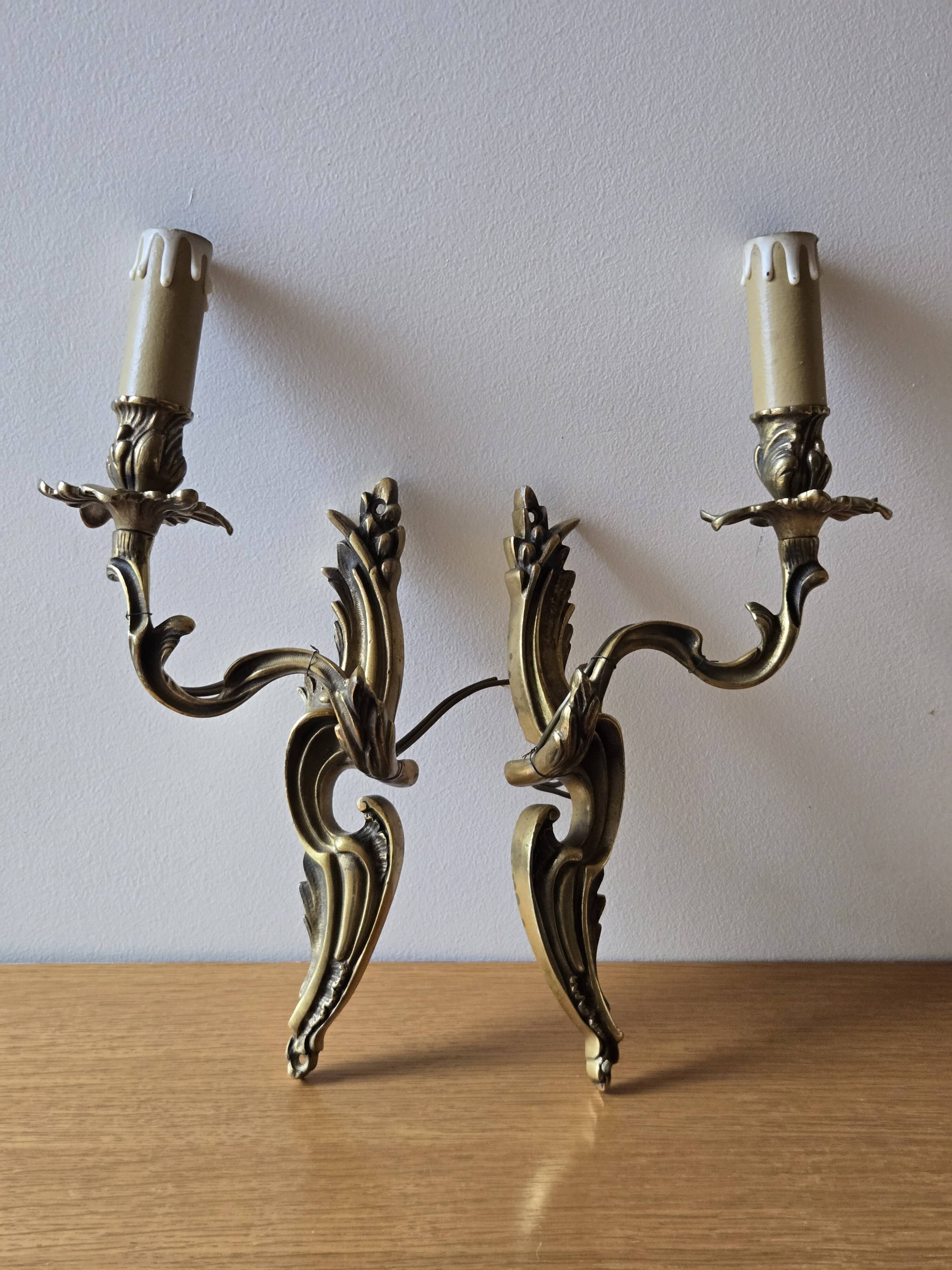 Pair of symmetrical gold wall sconces in baroque style made of bronze.