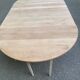 Large extendable round dining table stripped in solid cherry wood with a central leg.