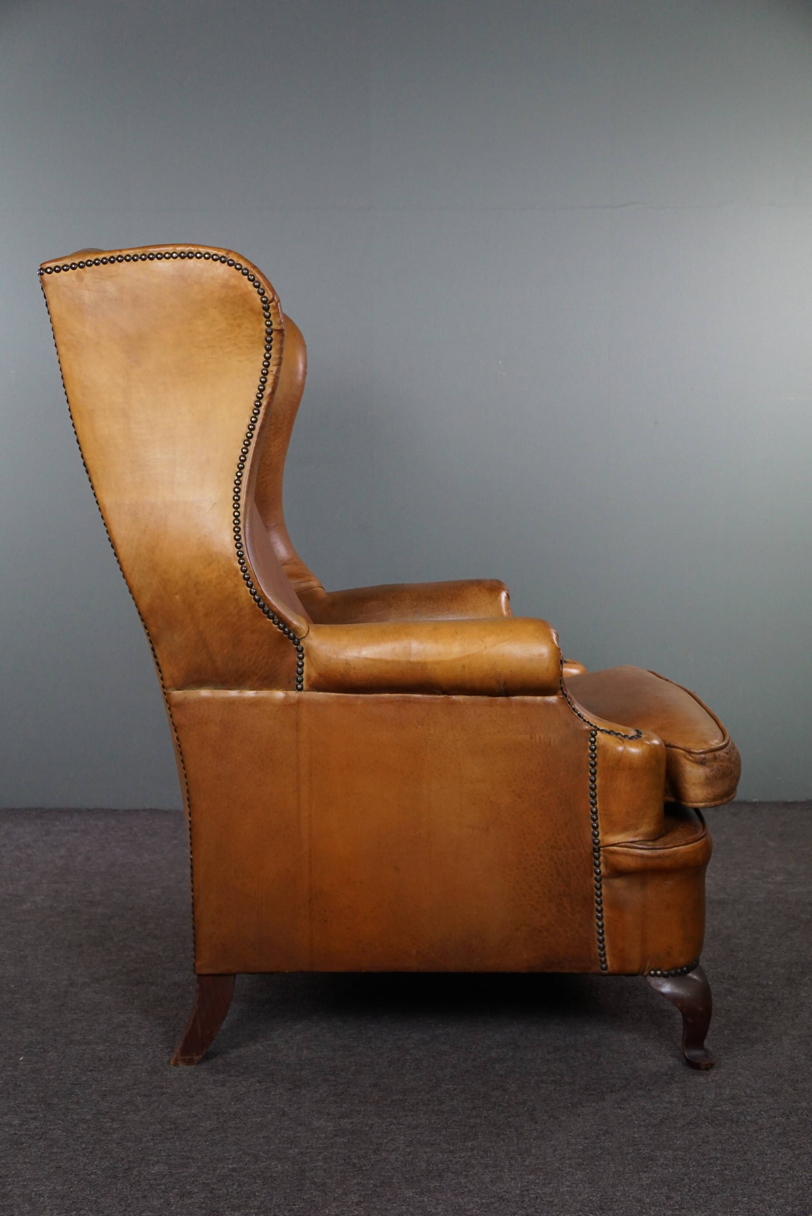 Old wingback armchair made of sheep leather in a correct condition