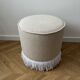 Pouf rond avec franges en bas, en bouclée crème.