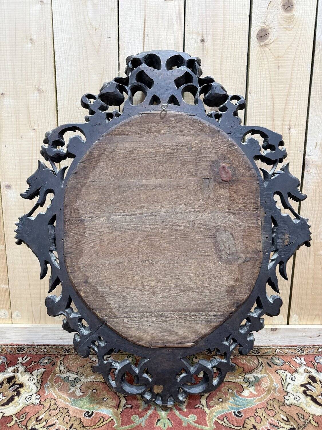 Oval mirror in carved wood with dragon heads.