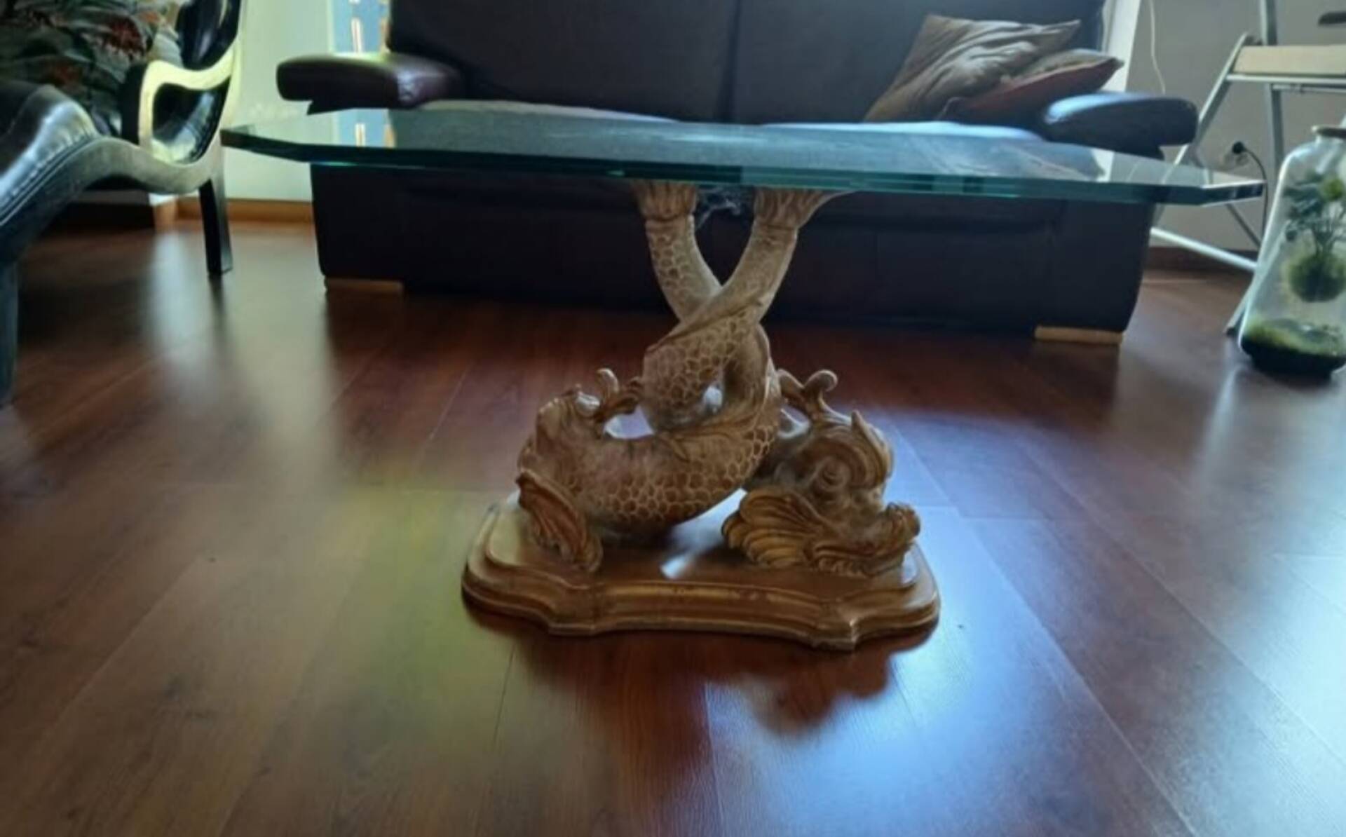 Glass table with carved wooden legs featuring intertwined fish.