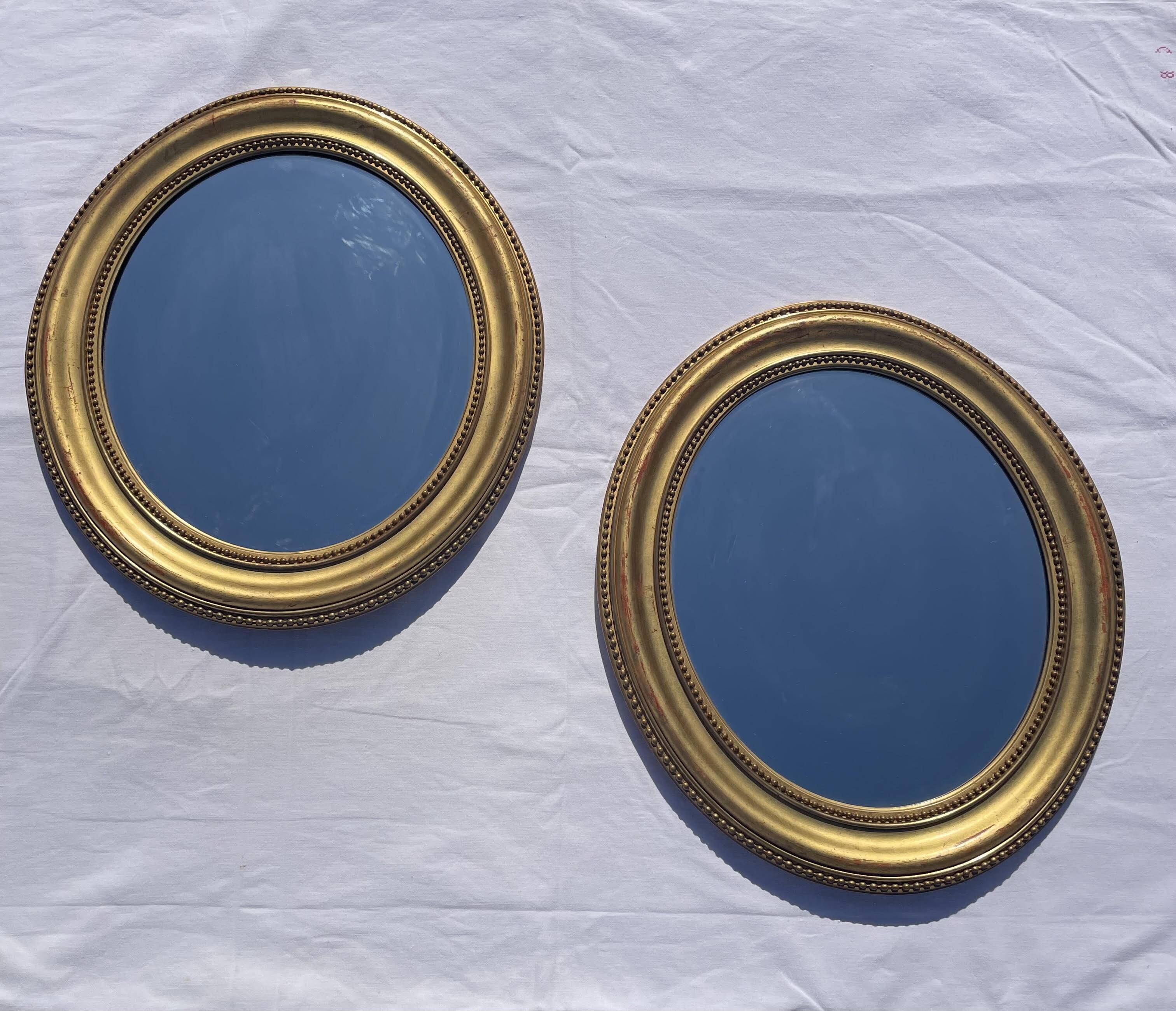 Duo de miroirs ovales et dorés en bois