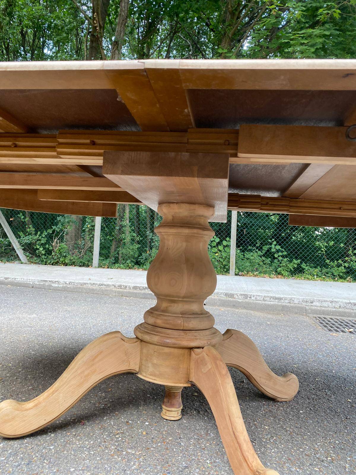 Round dining table with a central pedestal, extendable, stripped in solid walnut with 2 extensions.