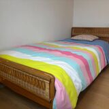 Vintage single bed made of rattan from the 1970s with a mattress.