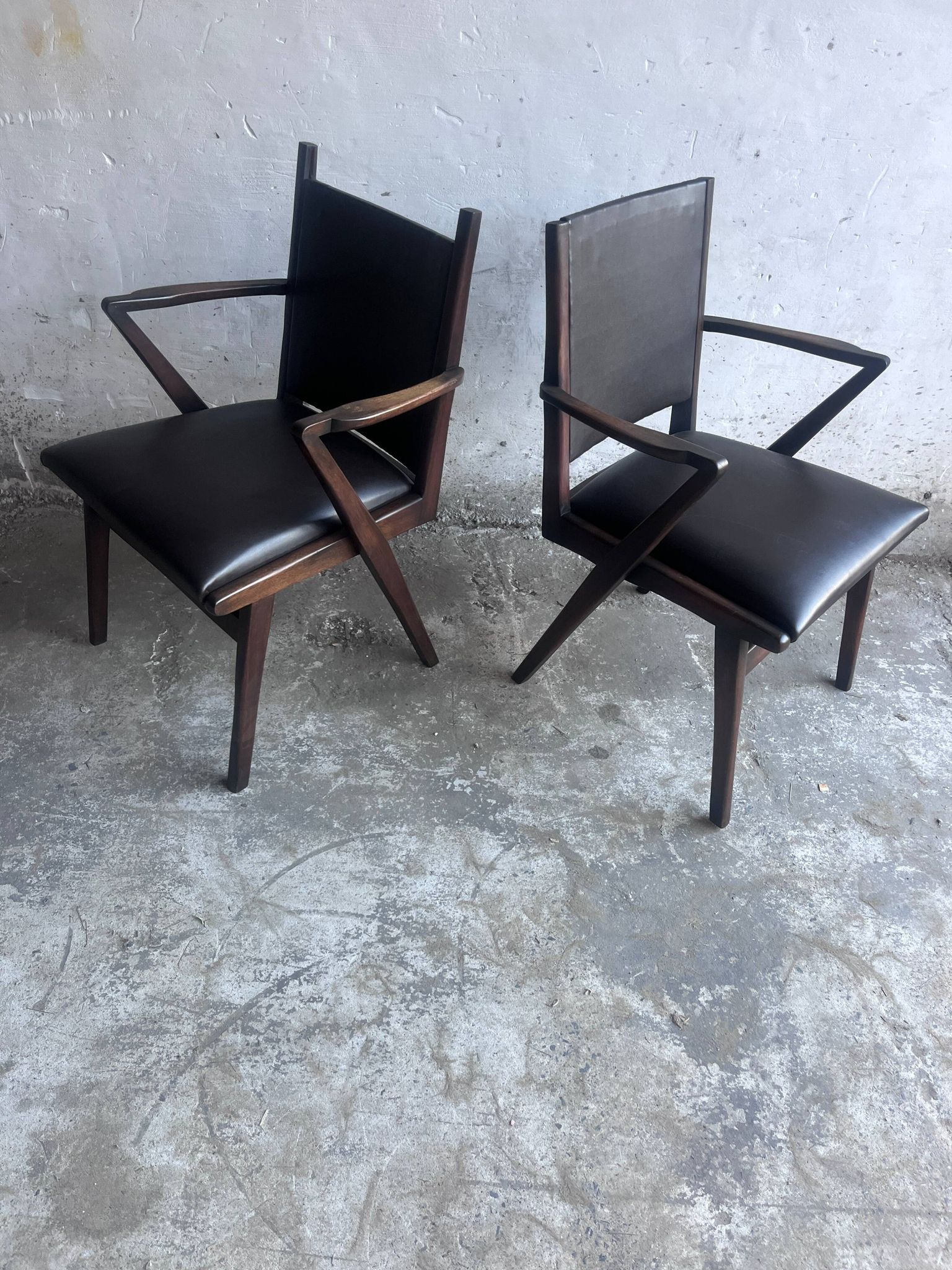 Pair of sculptural mid-century armchairs in dark wood and brown upholstery.