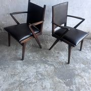 Pair of sculptural mid-century armchairs in dark wood and brown upholstery.