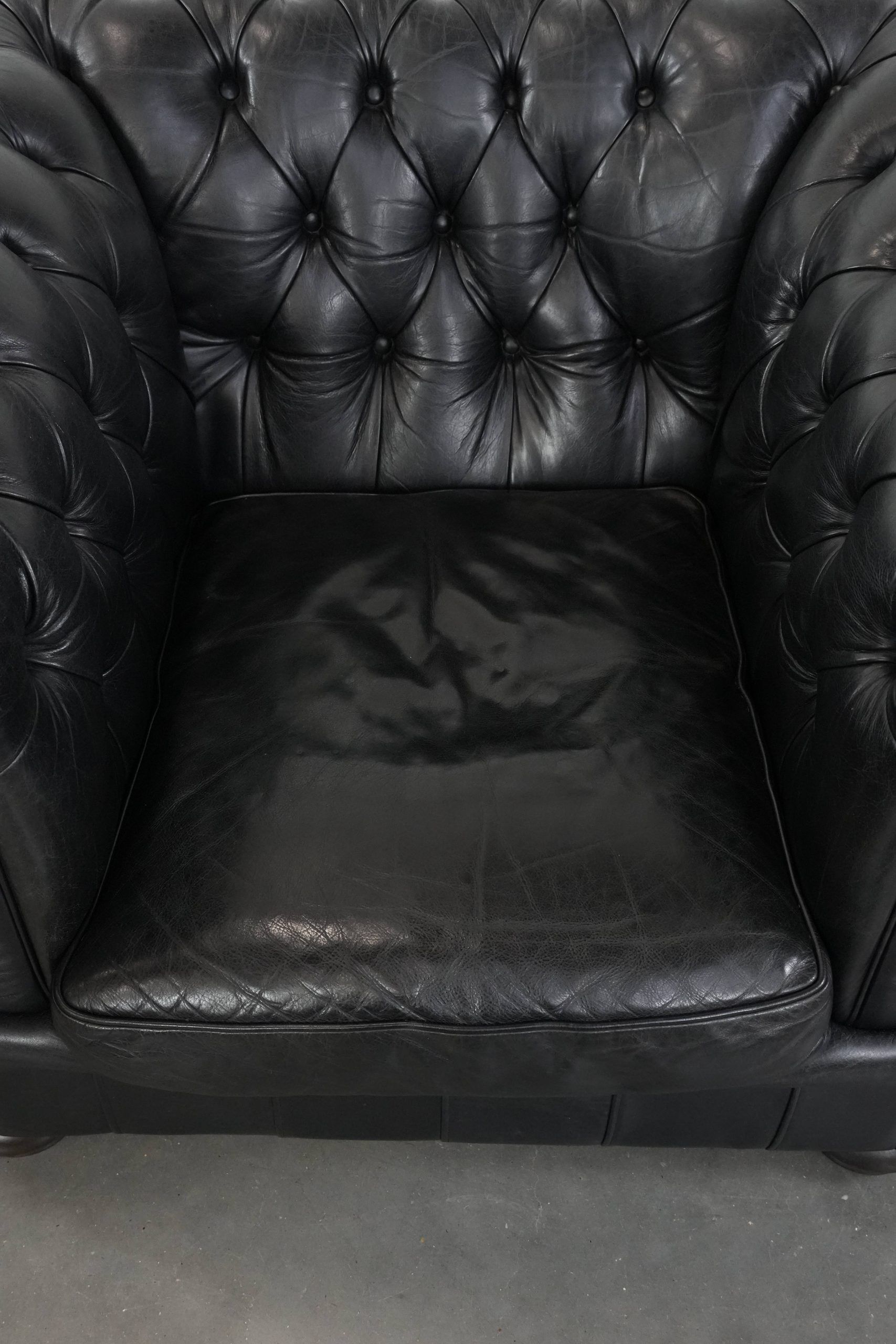 Comfortable black chesterfield armchair made of cowhide leather