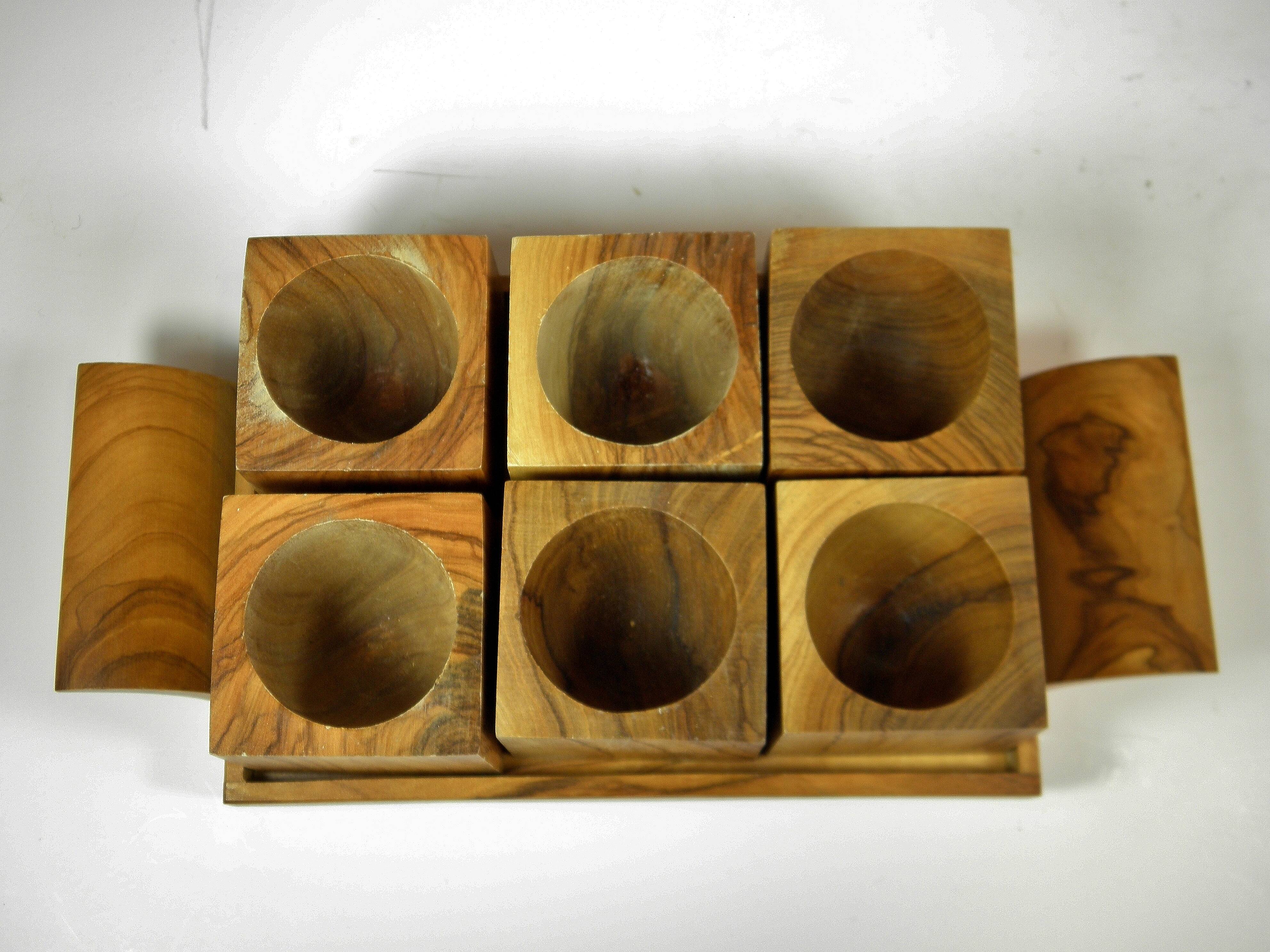 Six egg cups on a wooden tray.