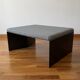 Minimalist/industrial coffee table with a black metal frame and a grey fabric top.