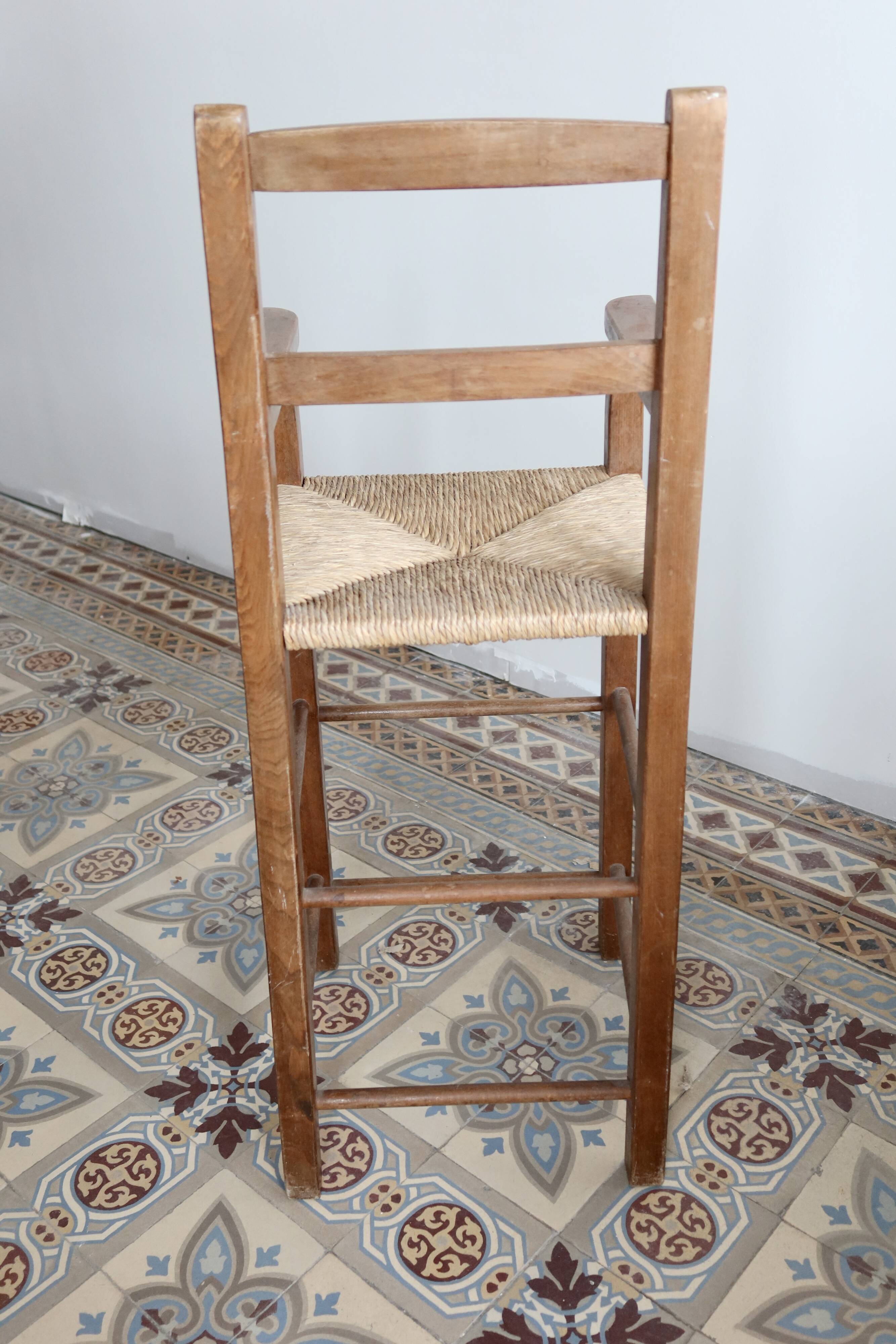 Vintage wooden high chair for children with a straw seat.