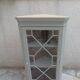 Vintage English corner display cabinet enhanced in grey-green with a wooden top.