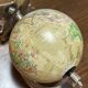 1960s terrestrial globe on a chrome stand with a plane flying over it.