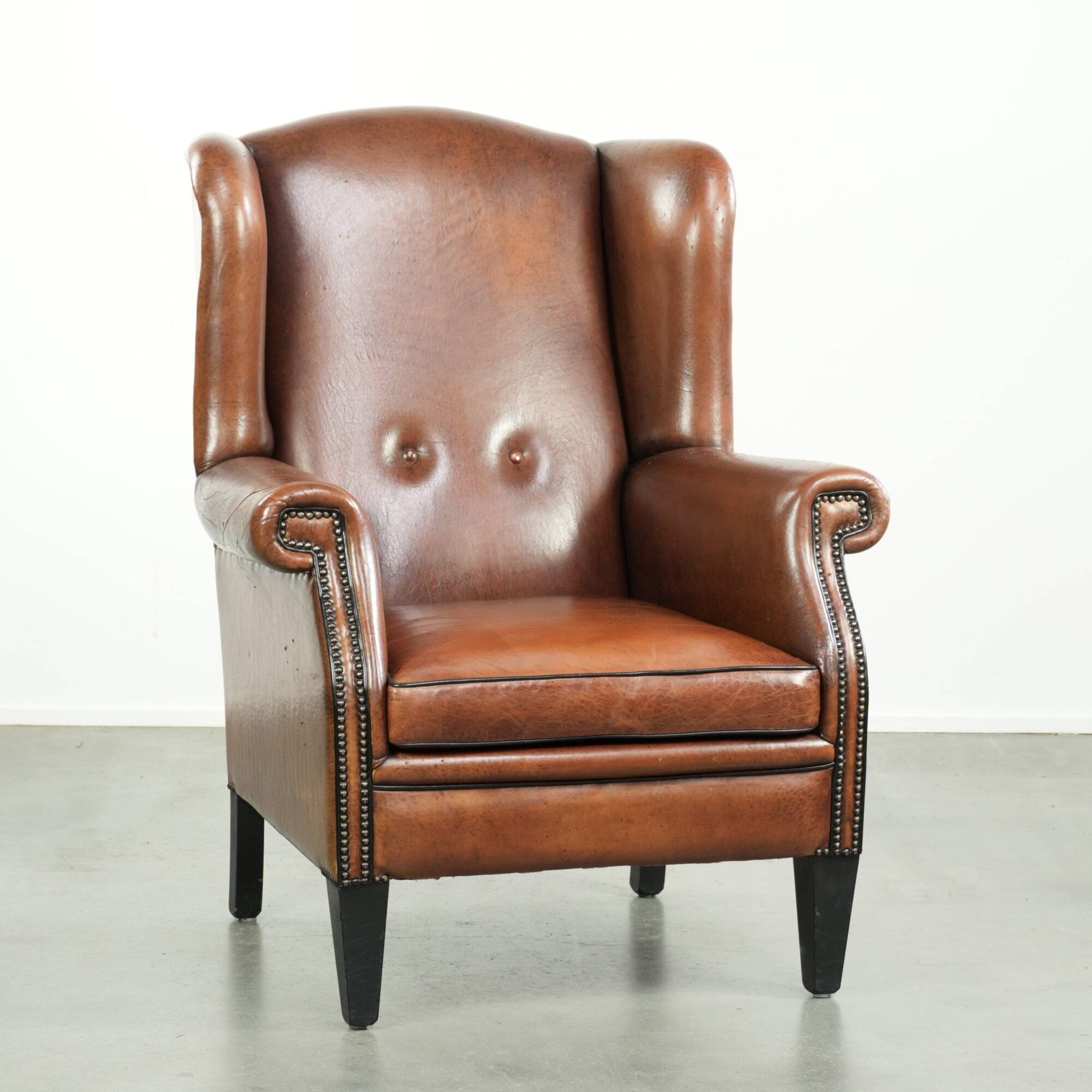 Sheepskin wingback armchair finished with black piping and a correct seat