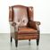 Sheepskin wingback armchair finished with black piping and a correct seat