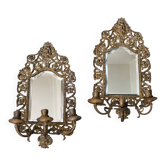 Pair of mirror wall sconces with brass candle holders.