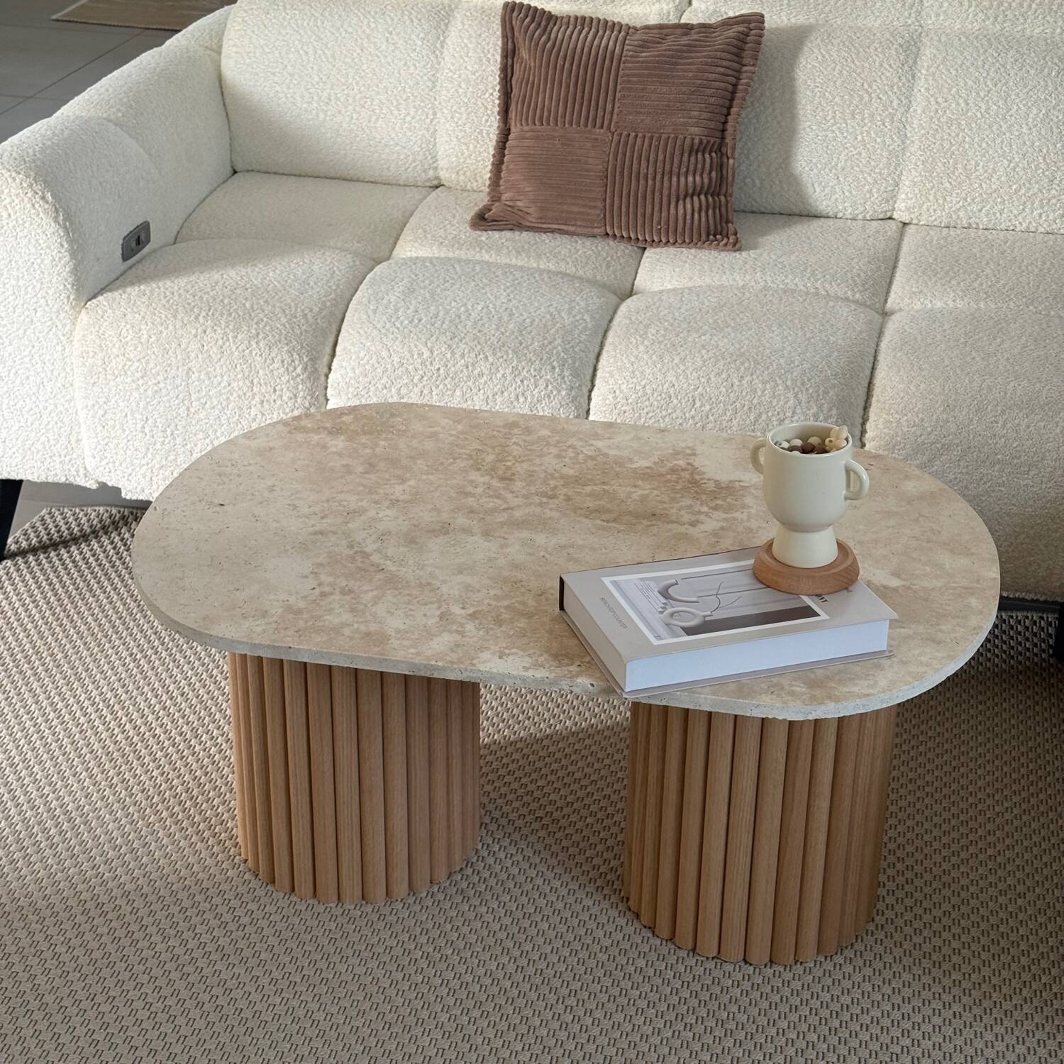 Oval coffee table in travertine and raw fluted wood.