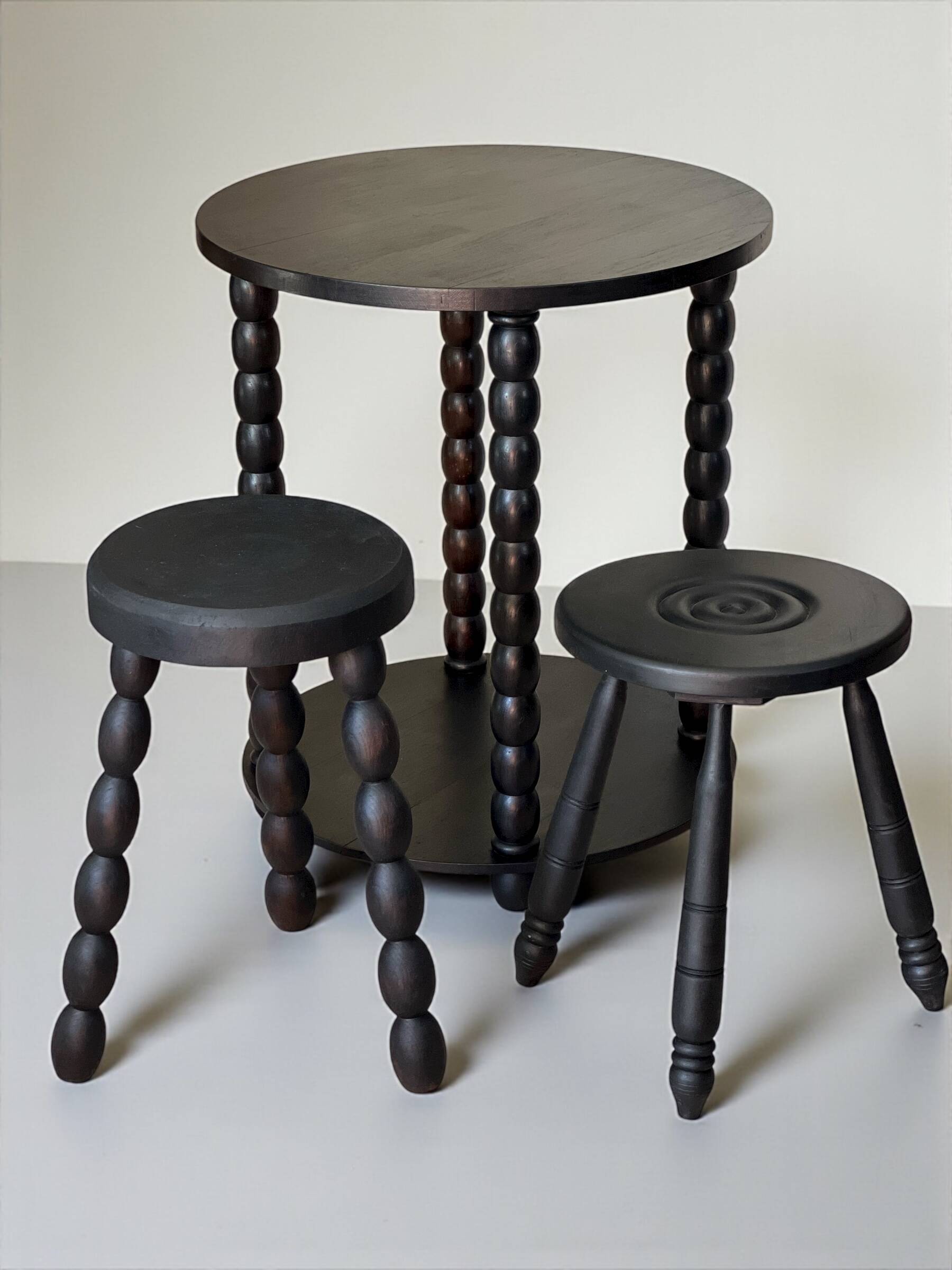 Set of side table and 2 stools, stained black wood, Circa 1950.
