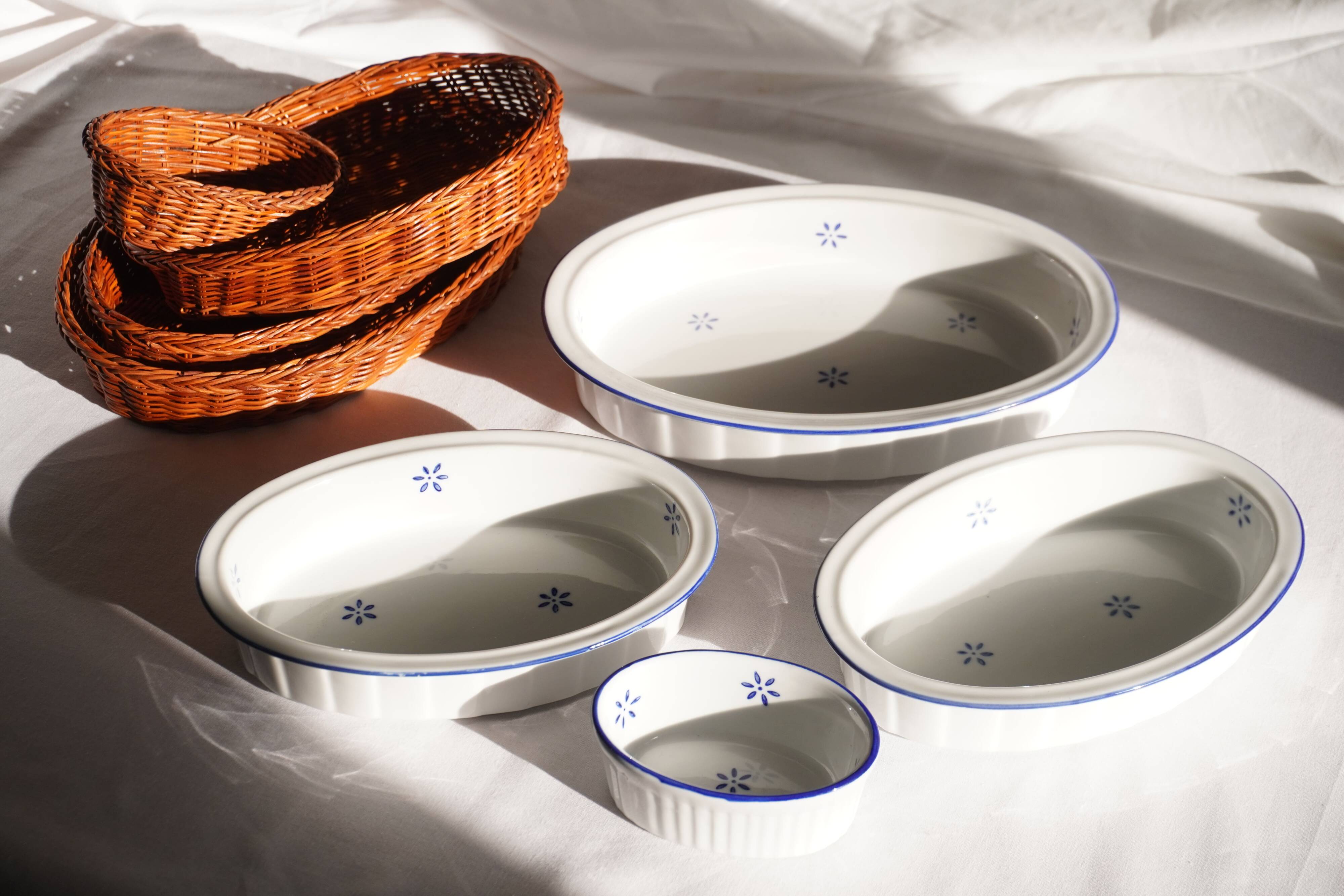Set of 4 white porcelain dishes with blue decorations and wicker stands