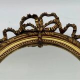 Antique oval gilded mirror with wooden frame and stucco detail
