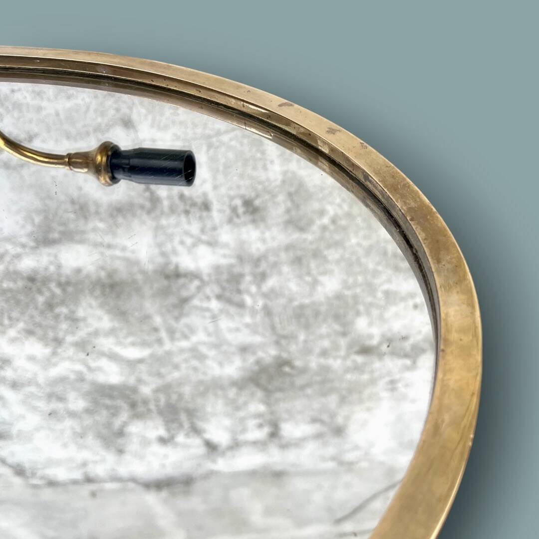 Oval wall mirror in gilded brass with double sconces – 1950s/60s