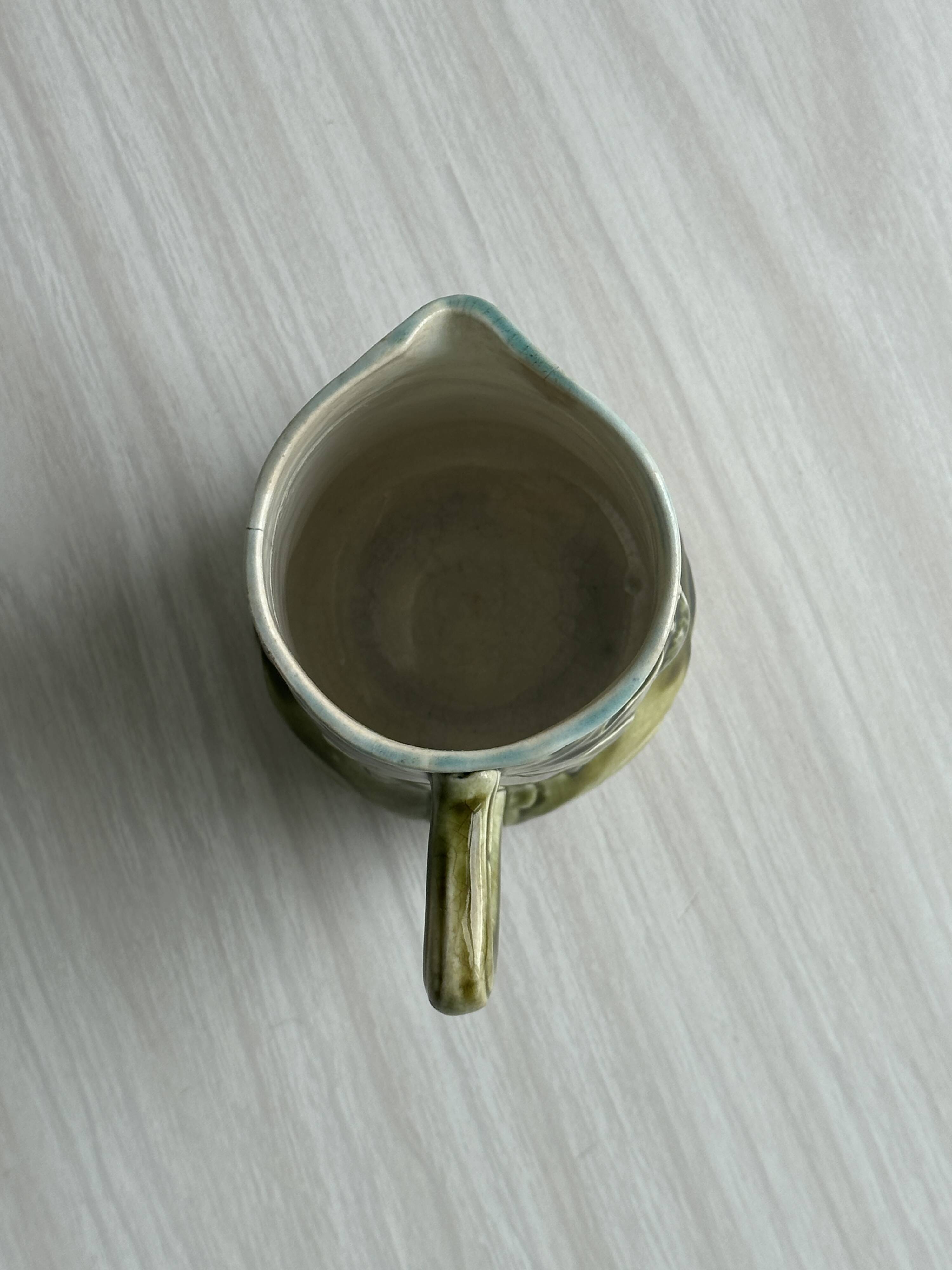 Green slip milk jug with floral patterns.