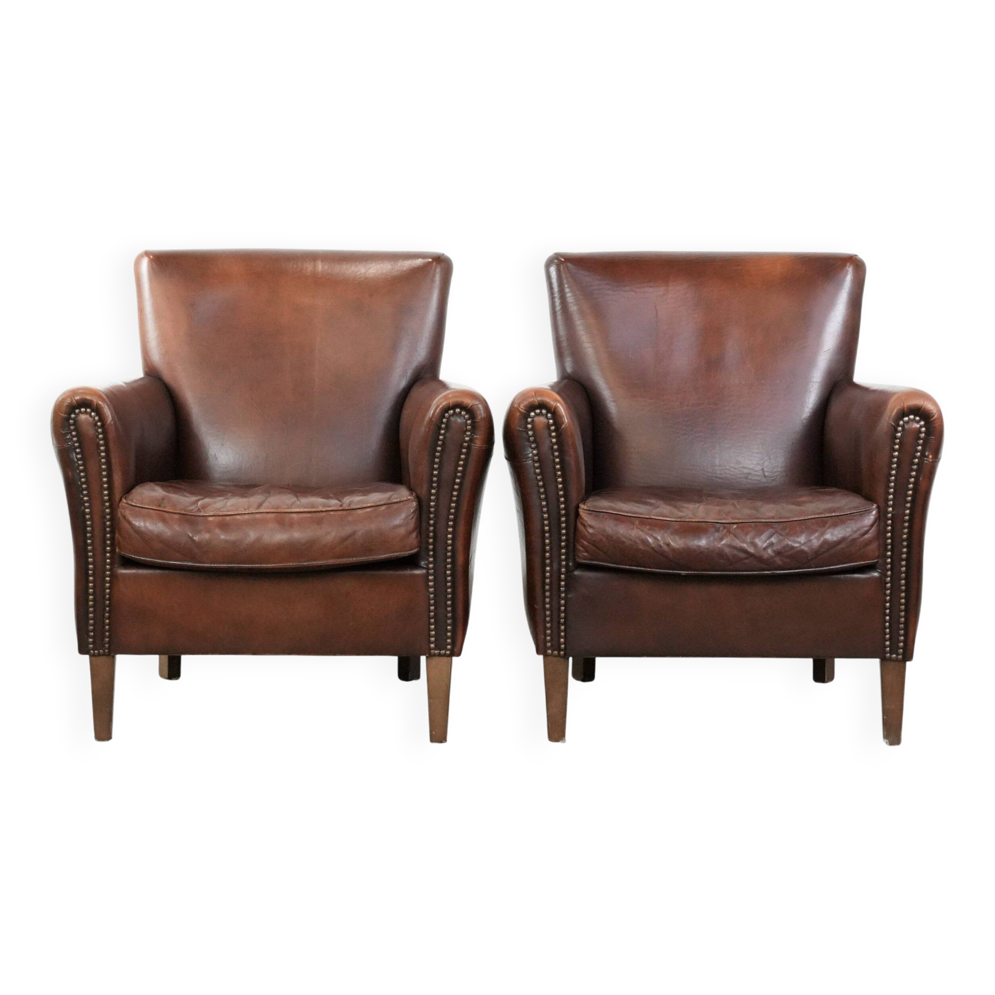 Ensemble de deux fauteuils en cuir de mouton vintage au caractère marqué.