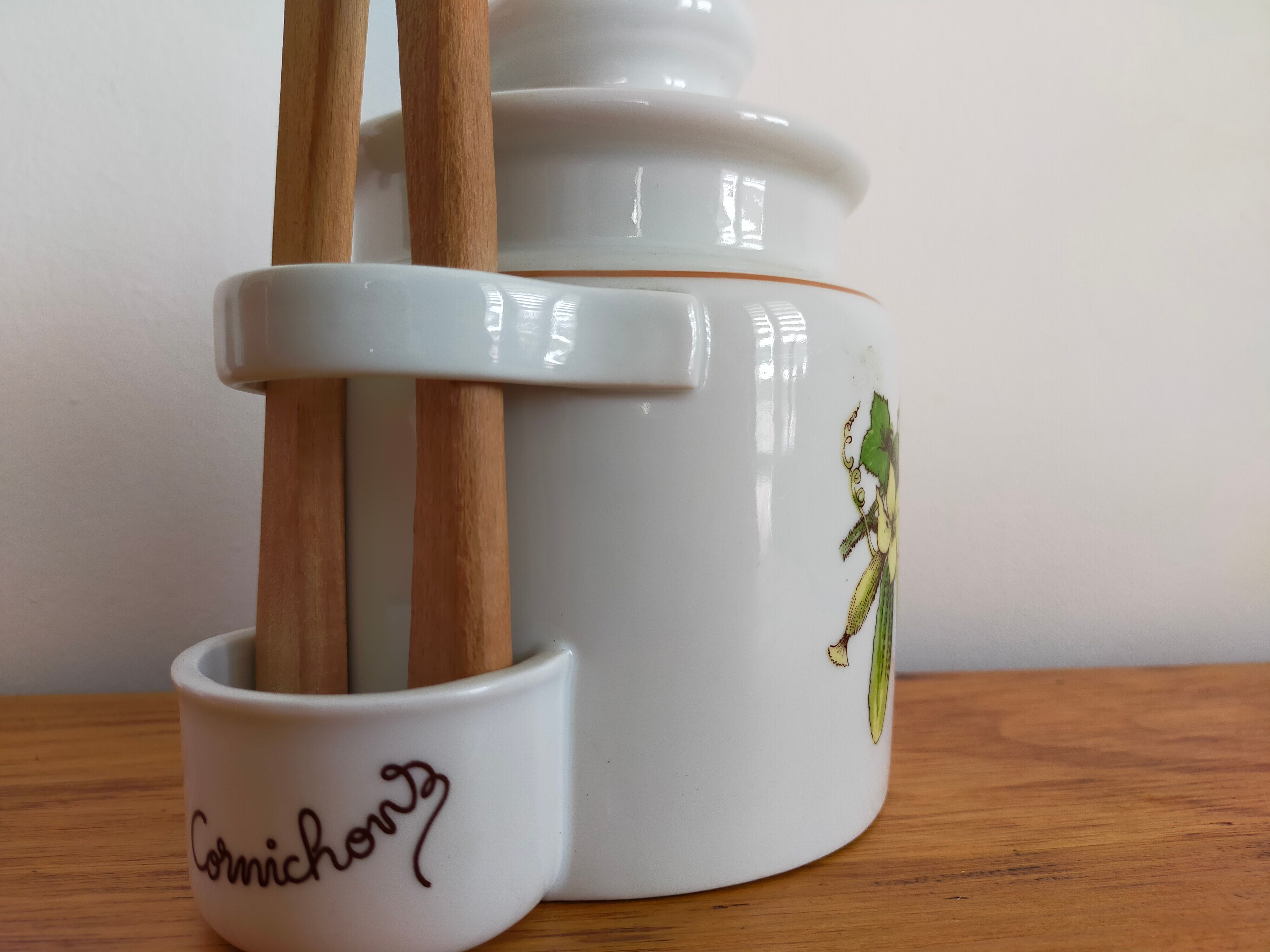 Vintage porcelain pickle pot with wooden pliers.