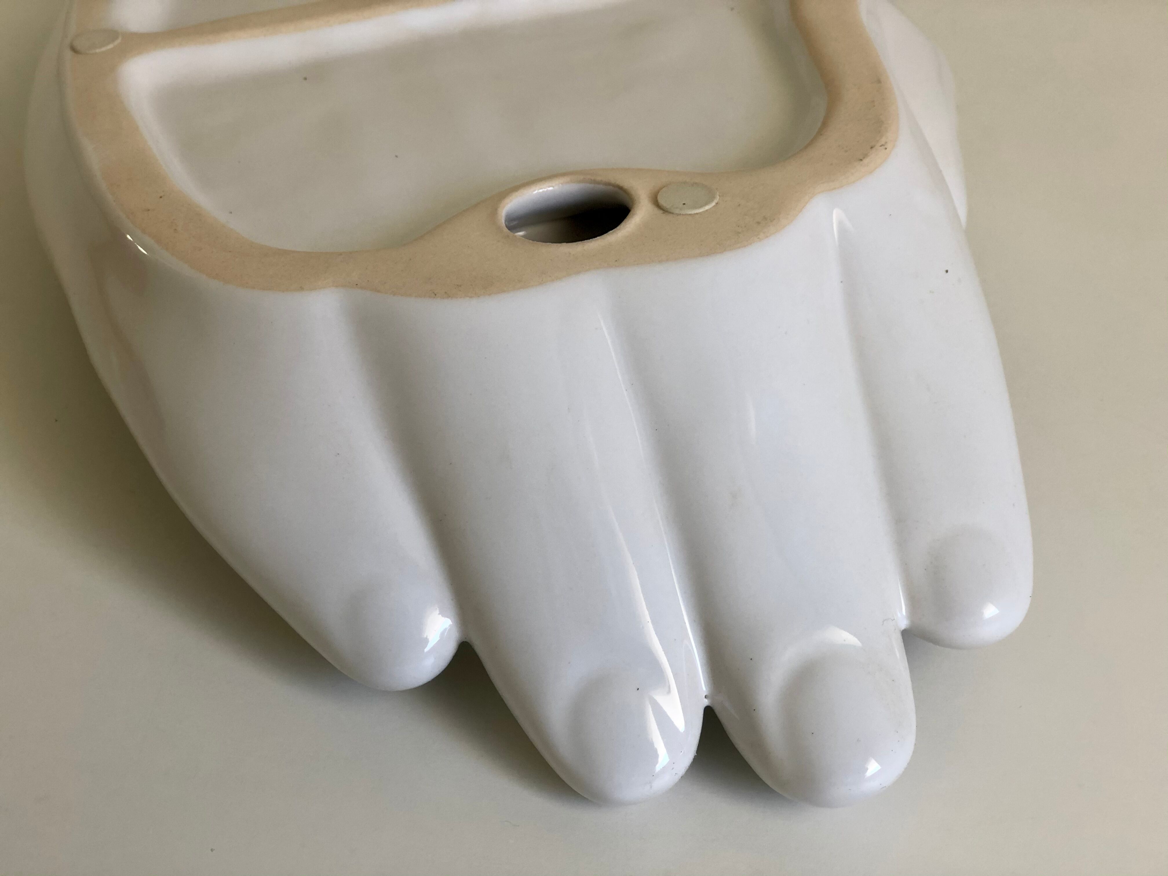 Empty white enamelled ceramic pocket in the shape of a large hand, 1990