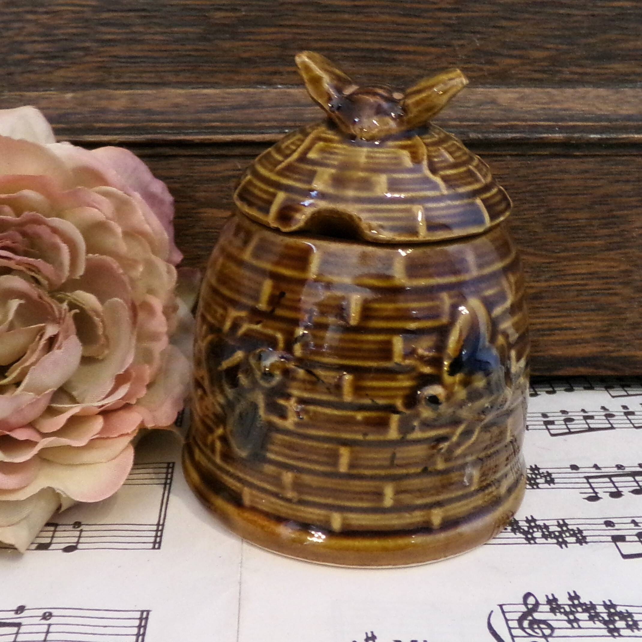 Honey pot in the shape of a hive decorated with bees.