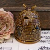 Honey pot in the shape of a hive decorated with bees.