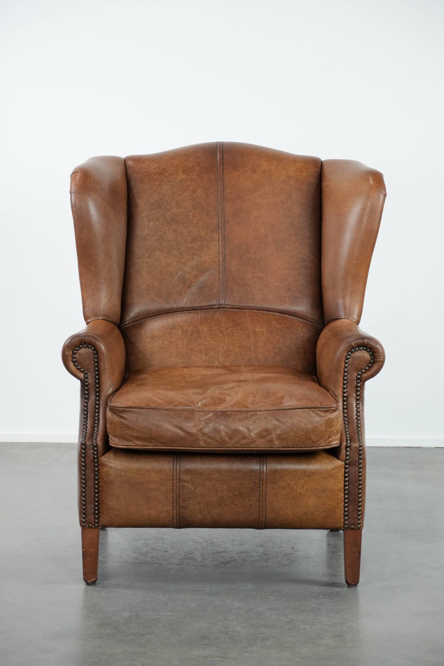 Cognac-coloured wingback armchair in English style made of cowhide leather