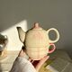 Vintage porcelain teapot and cup set with pink and beige floral and gingham pattern
