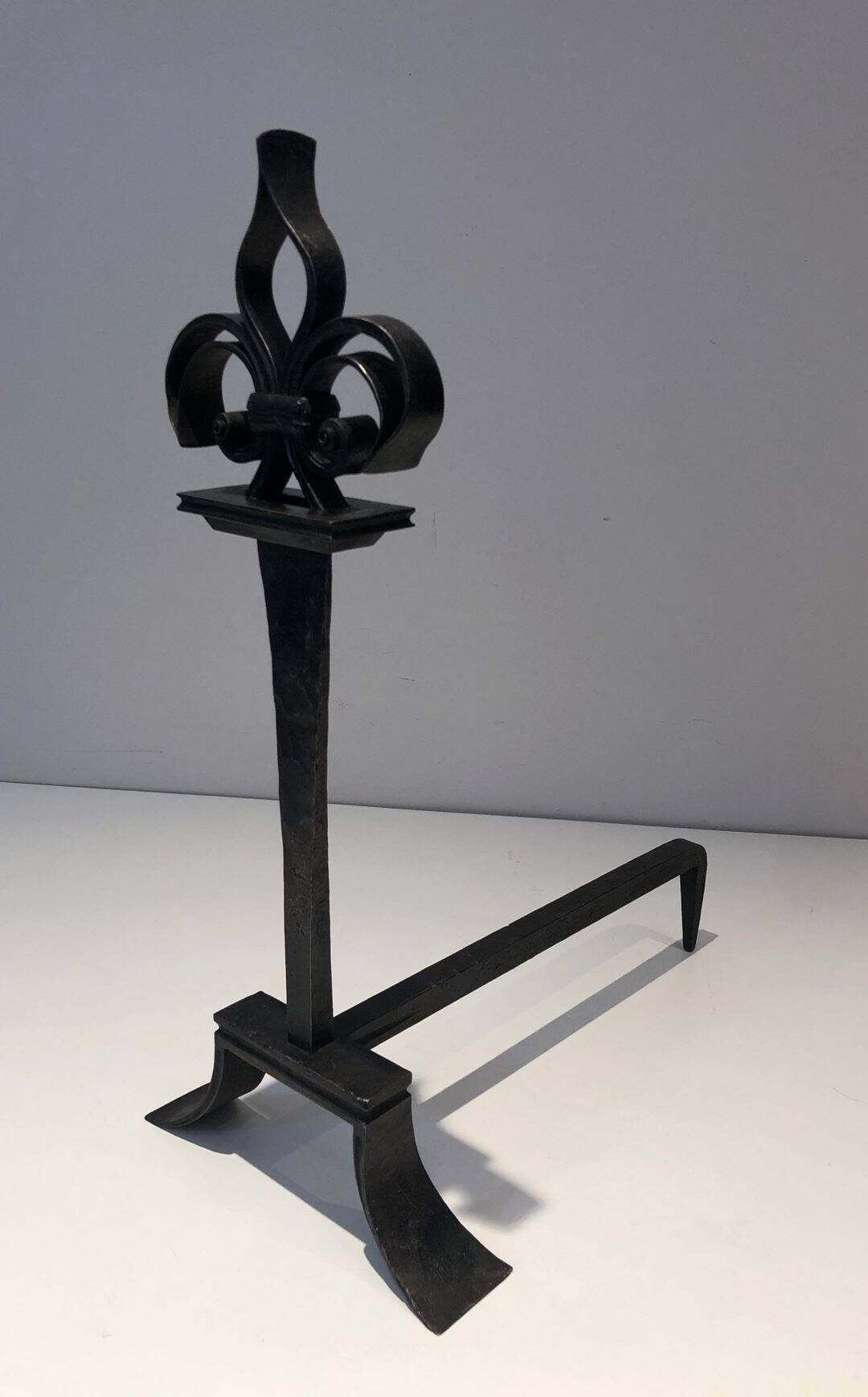 Important pair of wrought iron andirons with torch in heraldic fleur-de-lis design.