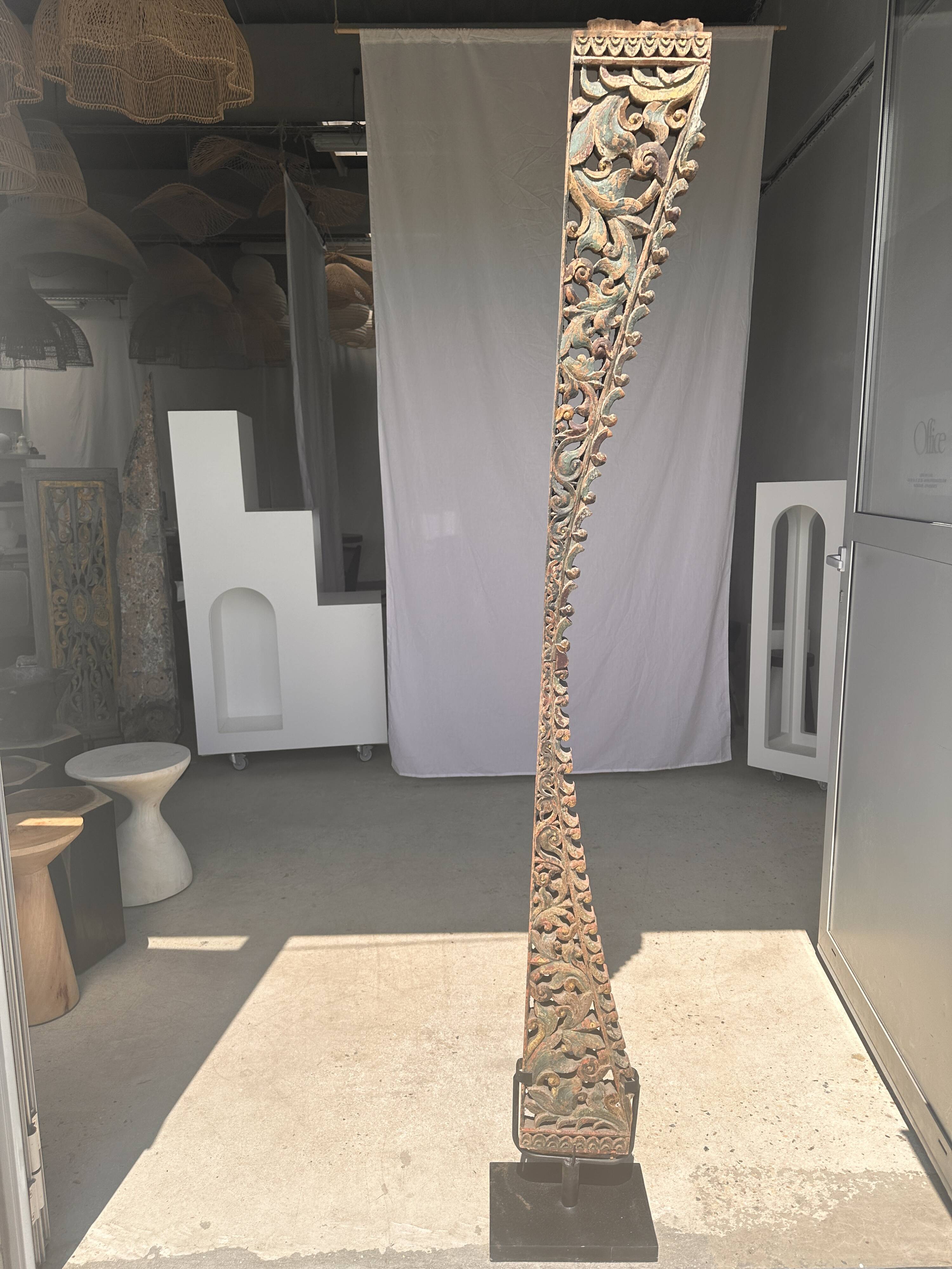 Indonesian construction element in carved wood with intertwined plant motifs mounted on a base (fri